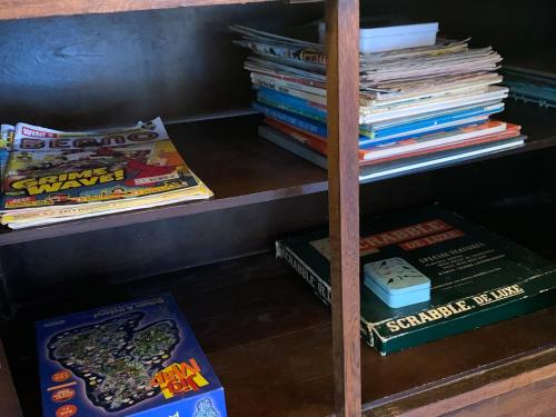 a book shelf filled with books next to a stack of books at The Organic Cabin - Uk42325 in Horsington