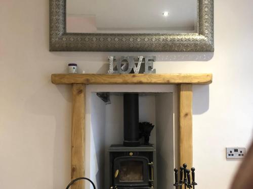 a mirror above a wood stove in a room at Copper Crab Cottage in Amlwch