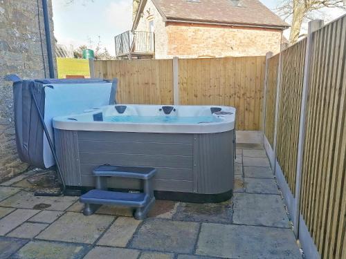 a bath tub sitting in a yard next to a fence at Colstey Farmhouse in Acton