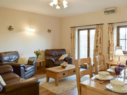 a living room with leather furniture and a table at Tan-Y-Derwwen in Mydroilin