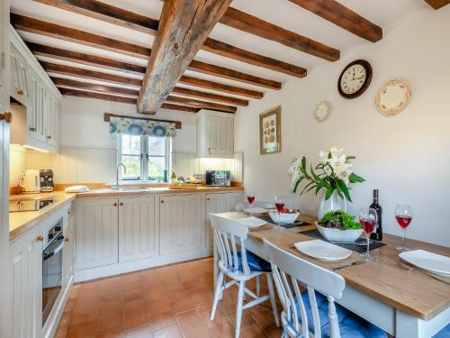 a kitchen with white cabinets and a wooden table with chairs at Swallow Cottages, No 2 - Uk46810 in Thurgarton
