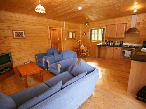 a living room with a blue couch and a kitchen at Auchenhill Lodge in Lochend