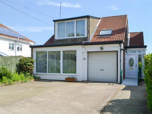 a white house with a garage and a fence at Dunpullin in Bedlington