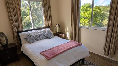 a bedroom with a bed with pillows and two windows at Villa Conochi in Philipsburg