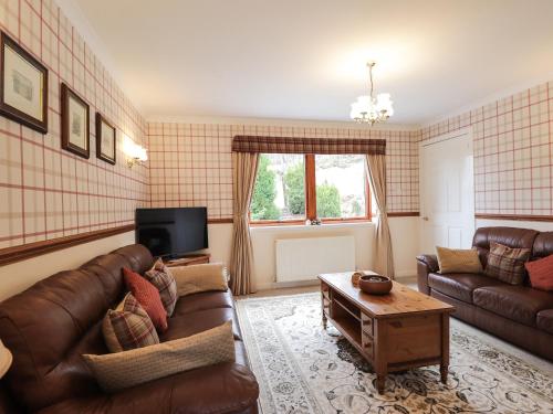 a living room with a couch and a table at Holly Cottage in Gorstan