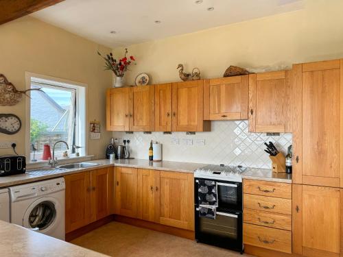 a kitchen with wooden cabinets and a stove top oven at The Green in Lochranza