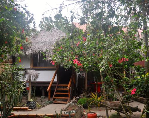 una pequeña casa con techo de paja y flores en Viejamar B&B, en Puerto López