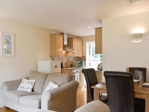 a living room with a couch and a kitchen at Endless Summer Cottage in Camelford