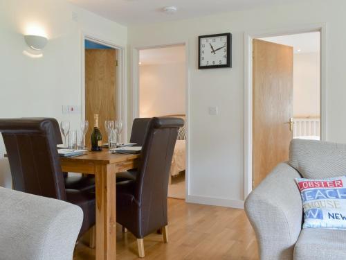 a dining room table with chairs and a clock on the wall at Endless Summer Cottage in Camelford