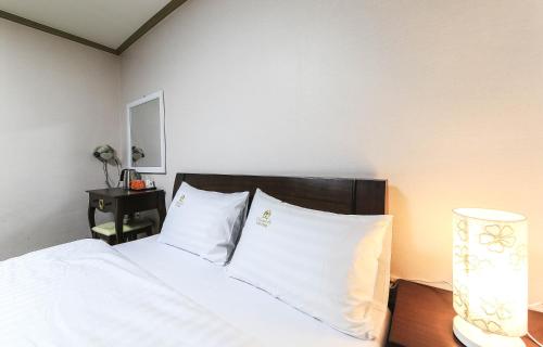 a bedroom with a bed with white sheets and a lamp at Crystal Residence Hotel in Daejeon