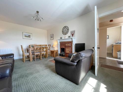 a living room with couches and a fireplace and a dining room at Pine Cottage - Dalcross in Dalcross