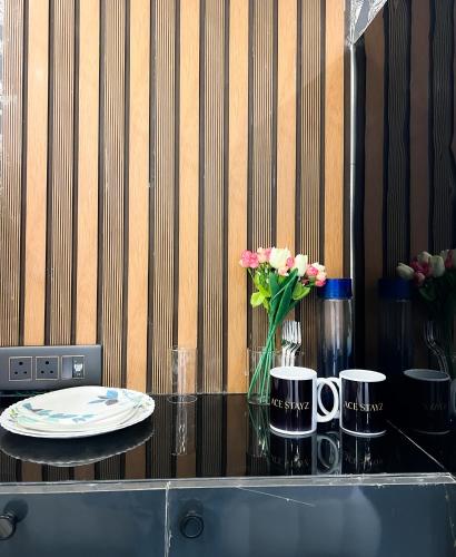 a glass table with a vase of flowers and two cups at The Boutique Studio Near Green Park Delhi- By ACESTAYZ in New Delhi