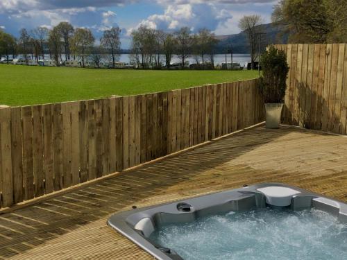 a bath tub sitting on a deck next to a fence at Clarinnes Cottage in Rowardennan