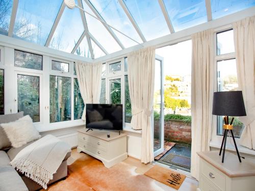a living room with a flat screen tv and windows at Rock House Apartment in Torquay