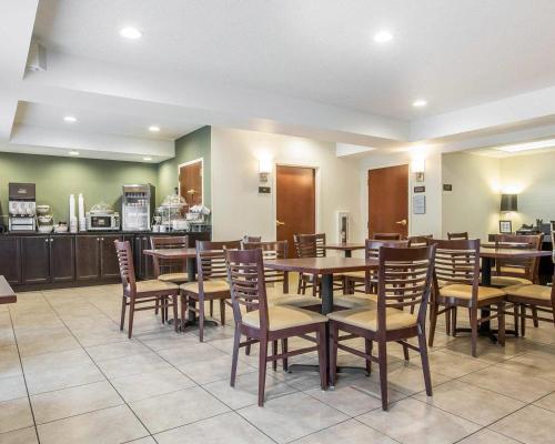 a restaurant with wooden tables and chairs and a kitchen at Sleep Inn & Suites Queensbury - Lake George in Queensbury