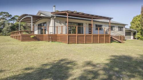 a house with a large deck on a yard at Bawley Backyard Haven - family retreat near beach in Bawley Point
