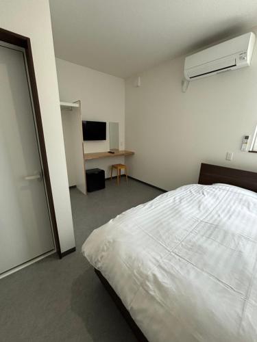 ein weißes Schlafzimmer mit Bett und Fernseher in der Unterkunft Cress 3 in Biei