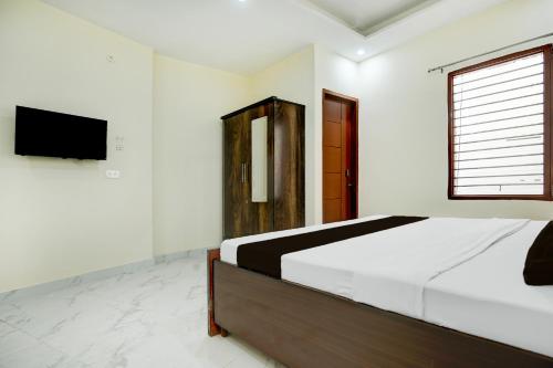 a white bedroom with a bed and a television at Hotel O Classic in in Kharar