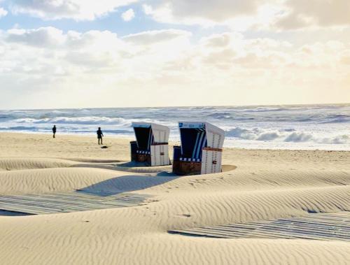 two beach chairs sitting on the sand on the beach at Haus Magnus SeaSide in Sylt