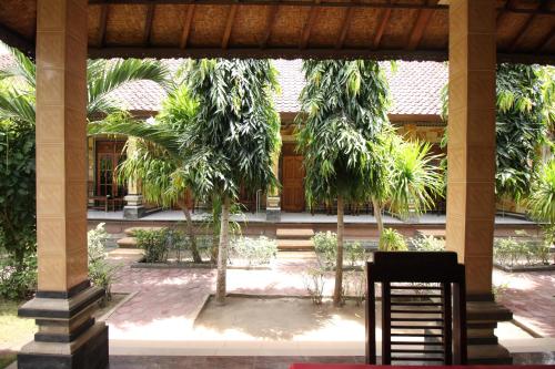 a chair sitting in front of a building with palm trees at Jepun Bali Bungalow in Nusa Lembongan