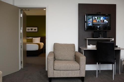 a room with a chair and a tv and a bed at Quest Rotorua Central in Rotorua