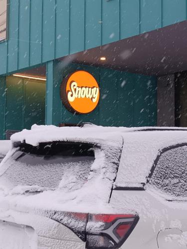 a snow covered car parked in front of a store at Tbox in Kutchan