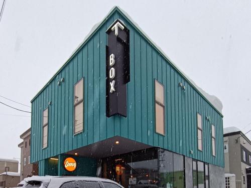 a green building with a sign on top of it at Tbox in Kutchan