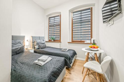 a bedroom with two beds and a table and window at Central Platinum Apartments 1 in Rybnik