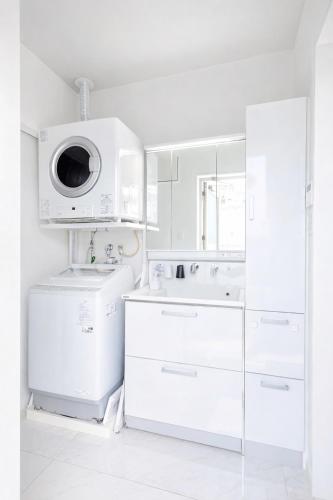 a white kitchen with a sink and a washing machine at Dual Life House Koza in Okinawa City