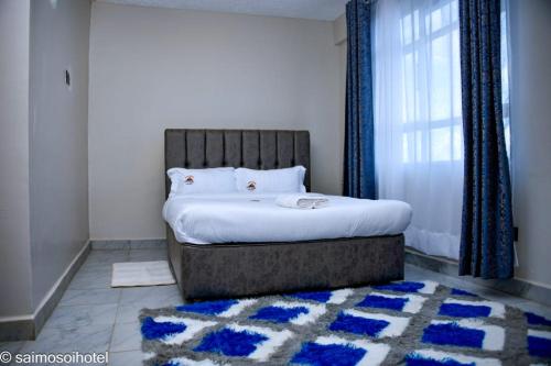 a bedroom with a bed with a window and a rug at Saimo Hotel-Kabarnet in Kabarnet