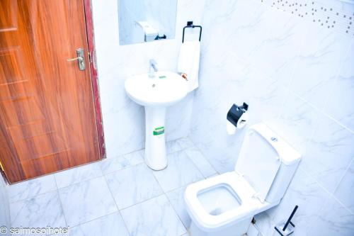 a white bathroom with a toilet and a sink at Saimo Hotel-Kabarnet in Kabarnet