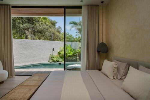 a bedroom with a bed and a view of a pool at Kono Villas & Resort in Ungasan