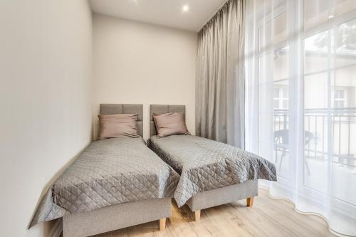a bedroom with two beds and a large window at Central Platinum Apartments 28 z balkonem in Rybnik