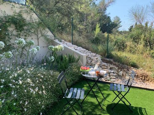 un jardin avec une table et des chaises sur la pelouse dans l'établissement Les 3 Pins, à Fontvieille