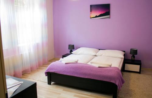 1 dormitorio con 1 cama con pared morada en Villa Zora, en Bardejovské Kúpele