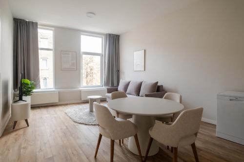 a white living room with a table and chairs at Comfortable 1-Bedroom Flat in Central Rotterdam in Rotterdam