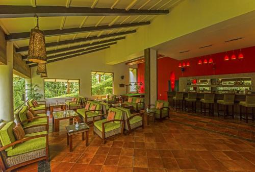 een restaurant met stoelen en tafels en een bar bij The Windflower Resort & Spa, Coorg in Suntikoppa