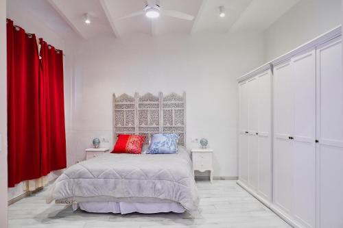 a white bedroom with a bed and red curtains at Apartamento Loft en el centro de Peralada in Peralada