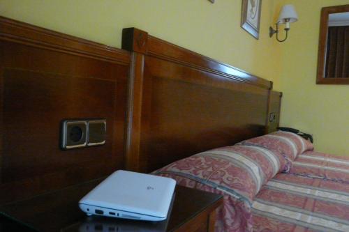a laptop computer sitting on a table next to a bed at Idh Angel in Oviedo