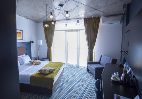 a hotel room with a bed and a chair and window at Aparthotel Tangerine in Batumi