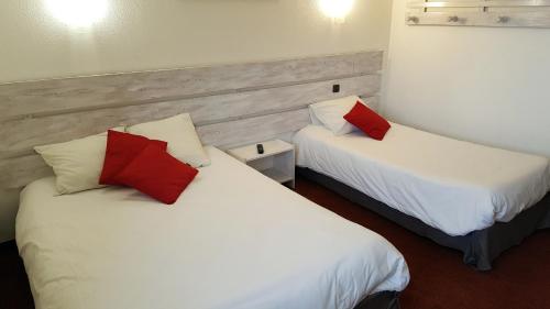 two beds in a room with white and red pillows at Hôtel Les Écrins in Les Orres