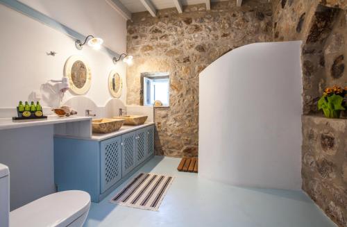 a bathroom with a white toilet and a stone wall at Theologos Houses in Grikos