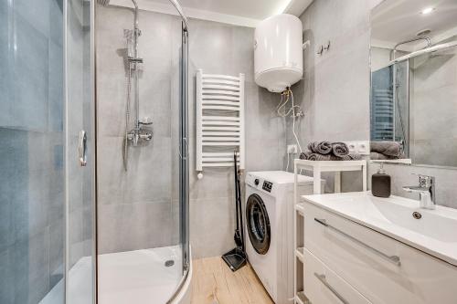 a bathroom with a shower and a sink and a washing machine at Central Platinum Apartments 15 in Rybnik