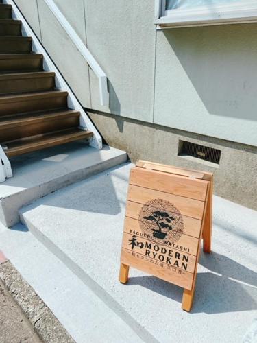 a wooden sign sitting on the side of a building at Wamodannooyado Yaguchinowatashi in Tokyo