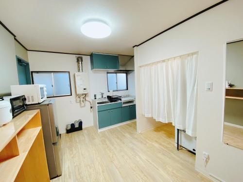 a room with a kitchen with blue cabinets and a kitchen at Wamodannooyado Yaguchinowatashi in Tokyo