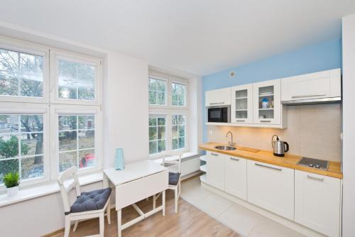 a kitchen with white cabinets and a table and chairs at YOURAPART Mariacka Starówka in Gdańsk