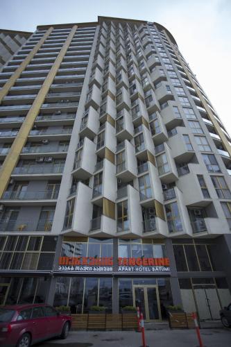 a tall building with a car parked in front of it at Aparthotel Tangerine in Batumi