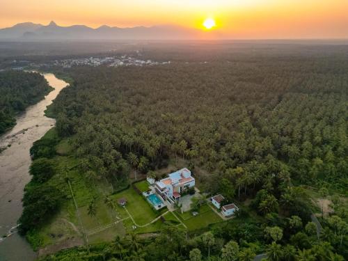 an aerial view of a house on a island next to a river at Pollachi Riverhouse, A CGH Earth Saha experience in Pollāchi