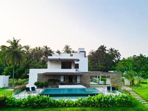 a house with a swimming pool in front of it at Pollachi Riverhouse, A CGH Earth Saha experience in Pollāchi