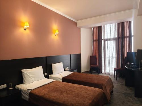 a hotel room with two beds and a television at Canyon Hills Hotel in Yerevan